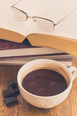 Cup of chocolate on wooden surface with books