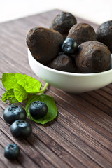 Chocolate truffles with blueberry and mint on wooden background