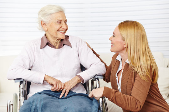Frau redet mit Seniorin im Rollstuhl