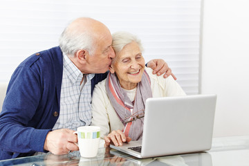 Mann küsst Seniorin mit Laptop
