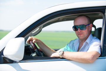 Naklejka premium Happy adult man in white new car at nature