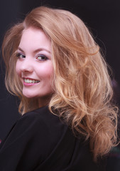 Obraz premium Smiling girl with blond wavy hair by hairdresser in beauty salon