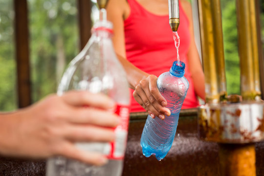 Young woman fillig a plastic bottle with healthy mineral water