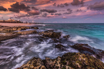 Fototapeta na wymiar Purple sunset over a tropical rocky beach