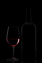 Red wine bottle and wine glass on black background