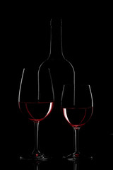 Red wine bottle and wine glass on black background