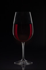 Red wine glass with wine on black background