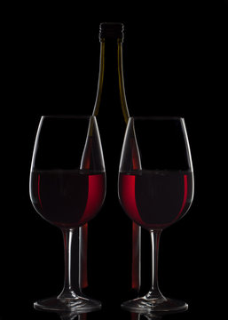 Red wine bottle and two wine glasses on black background