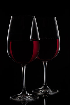 Two red wine glasses with wine on black background