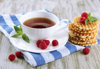 Cup of tea with cookies and raspberries on table close-up