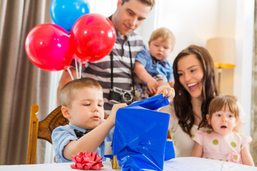 Fototapeta na wymiar Family Looking At Birthday Boy Opening Gift Box