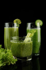 Glasses of green vegetable juice and salad isolated on black