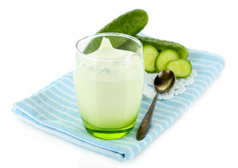 Cucumber yogurt in glass, on color napkin, isolated on white
