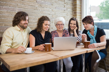 Woman With Friends Using Laptop At Coffeeshop
