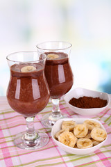Cocktails with banana and chocolate on table on light
