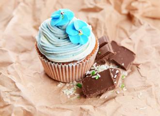 Tasty cupcake with butter cream, on color background
