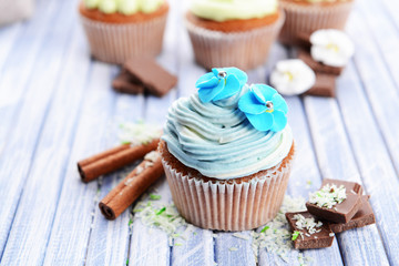 Tasty cupcakes with butter cream, on color wooden background