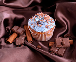 Tasty cupcake with butter cream, on color fabric background