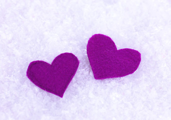 Little felt hearts on snowy background