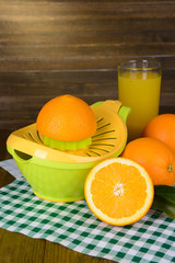 Citrus press and oranges on table on wooden background