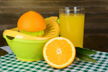 Citrus press and oranges on table on wooden background