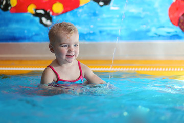 Fototapeta na wymiar Adorable happy baby or toddler girl having fun in swimming pool