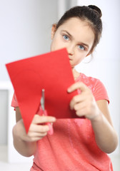 Dziecko wycina z papieru czerwone serce - obrazy, fototapety, plakaty