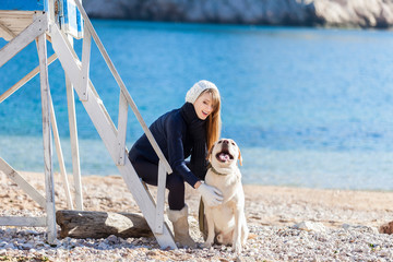 Beautiful young woman playing with dog on the sea shore