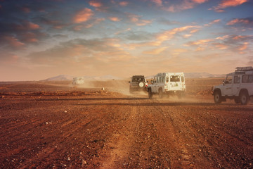 Cars in the desert at sunset - obrazy, fototapety, plakaty