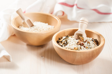 Rice in wooden bowl with ingredients for risotto
