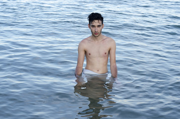 Beautiful man in swimsuit relaxing in sea during summer vacation