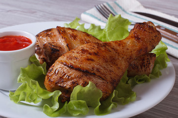 roasted chicken legs with lettuce and ketchup on a white plate