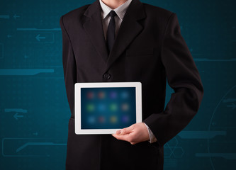 Businessman holding a white modern tablet with blurry apps