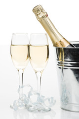 Champagne bottle in bucket with ice and glasses of champagne