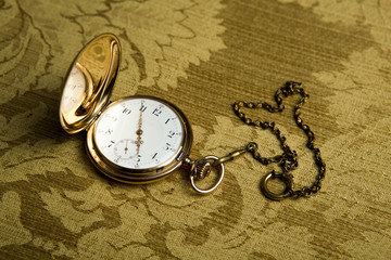Gold pocket watch on gold cloth