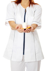 Young female nurse holding pills.