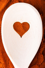 Heart shape made from spice on a wooden spoon.