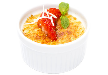 creme brulee garnished with strawberries on a white background