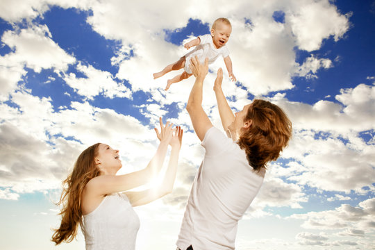Happy Family Throws Up Baby Boy Against Blue Sky