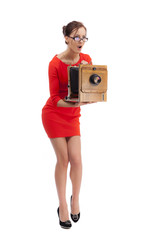 Girl in red dress with an old camera on a white background