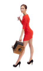 Girl in red dress with an old camera on a white background