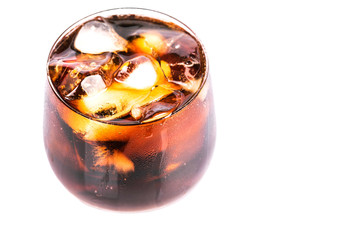 Cola drink with ice cubes in a short glass over white background