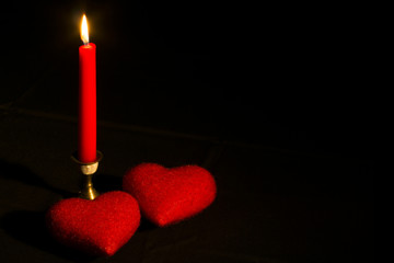Burning candle with two hearts