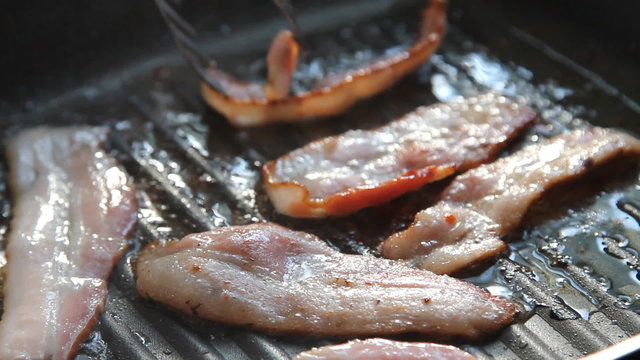 Bacon rashers frying in hot non-stick pan