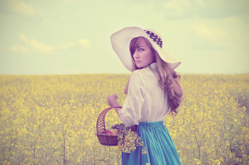 Young woman with basket at canola field