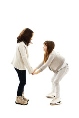 A girl teaching her sister to skate on ice
