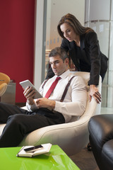 Businesswoman looking over male colleagues shoulder pointing at digital tablet