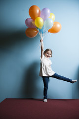 Fototapeta na wymiar Young girl pretending to be lifted up by bunch of balloons