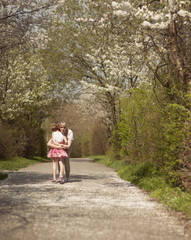 Mother hugging young girl in distance in a park