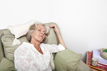 Tired senior woman sleeping on armchair at home